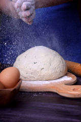 The baker is clapping hands covered with flour over the yeast dough