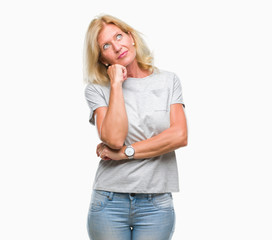 Middle age blonde woman over isolated background with hand on chin thinking about question, pensive expression. Smiling with thoughtful face. Doubt concept.