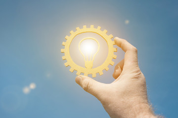 A burning lamp is an idea in the businessman's hand, against the sky. Business concept, innovation,...