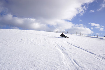 Einsamer Mann beim Rodeln, Winterfreude und Schlittenspass in Bayern