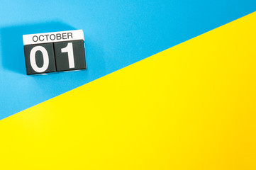 October 1st. Day 1 of month, wooden color calendar on blue and yellow background. Autumn time....