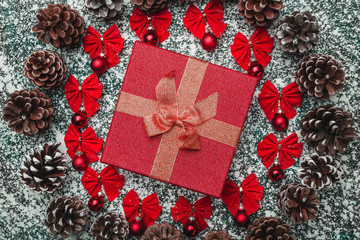 Upper, top, view from above of a Christmas present box inside of a circle created from red bows...