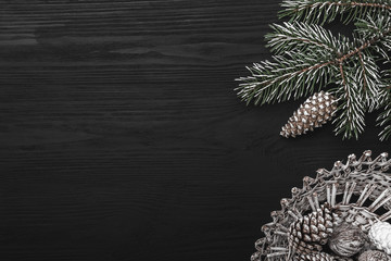 On a black background, a fir tree with cone and decorative objects. Space for a message of winter holidays. Top view.