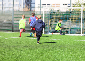  boys in red and blue, green uniforms play football with team on the green grass. Team game, training, active lifestyle, hobby, sport for kids concept
