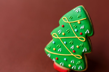 Christmas holiday sweets. Christmas holiday traditions. Christmas tree gingerbread on dark red background.Copy space