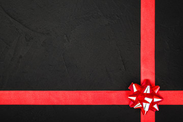 Upper top view of a red ribbon,on a stone black background, with space for text writing