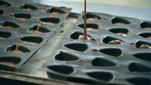 Delicious molten chocolate filling triangle shaped candy molds during candy production process at factory