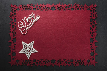 Merry Christmas inscription on red cloth background and wooden handmade star, view from above with free space for text writing.