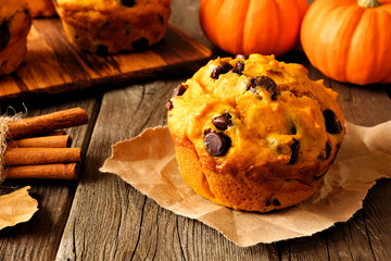 Autumn pumpkin chocolate chip muffin. Close up table scene on a rustic wood background.