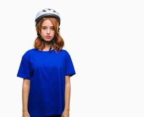 Young beautiful woman wearing cyclist helmet over isolated background with serious expression on face. Simple and natural looking at the camera.