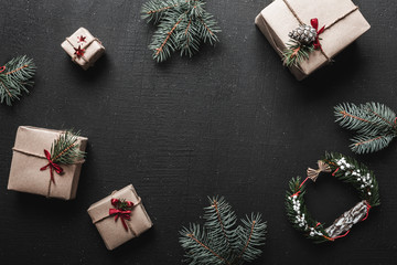 Christmas decoration, gift boxes and fir twigs, top view with copy space on black table surface....