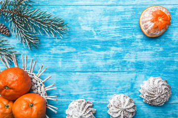 Azure wood background. Green fir tree. Sweets. Fruit with mandarin. Space for Christmas Message or New Year. Xmas and Happy New Year composition. Flat lay, top view