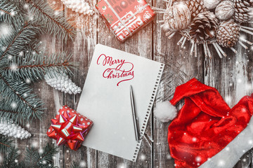 Old wood background, green fir tree. Merry Christmas message, Santa's hat and gifts. Greeting card...