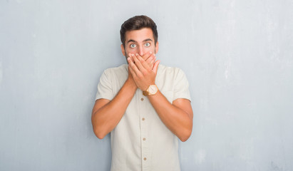 Handsome young man over grey grunge wall wearing summer shirt shocked covering mouth with hands for mistake. Secret concept.