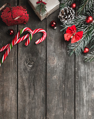 Christmas theme with fir branches, red bows and globes, cones, present boxes, cookies and candies, on rustic dark wooden background viewed from above, top, greeting card with space for text