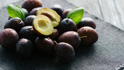 Beautiful composition of wet delicious plums with juicy flesh composed in heap on gray napkin in daylight
