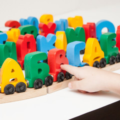 Obraz premium Russian wooden letters train alphabet with locomotive. Bright colors of red yellow green and blue on a white background. Early childhood education, learning to read, preschool and kids game concept.