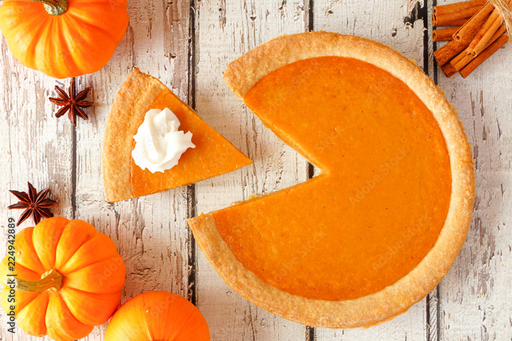 Poster Pumpkin pie with slice removed.  Top view table scene on a rustic white wood background.