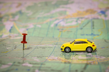 A yellow passenger car travels by geographic map. Route of movement on the world map. The concept of travel. Selective focus