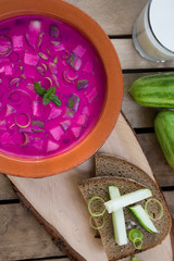Traditional lithuanian vegetable soup made of beetroot (beet), cucumber, dill, green onion and sour cream (kefir) on the wood backgound with ingredients, vertical