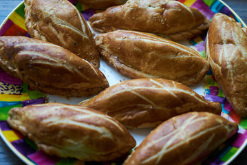 Fresh patties plate on wooden table background, close-up. Puff pastry patties filled with meat and vegetables. 
