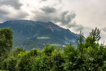 Alpen Berg mit Wolken. Bäume im Vordergrund