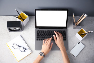 Female blogger using laptop at table, top view. Blank screen for mockup