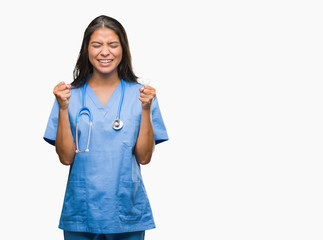 Young arab doctor surgeon woman over isolated background excited for success with arms raised...