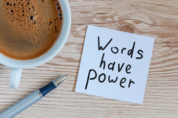 Words have power concept. Motivating and inspiring note at wooden table with morning coffee cup