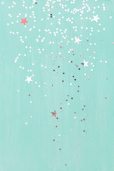Top view on old wooden turquoise table or background with shiny stars. Christmas, winter and holidays season concept.