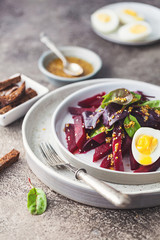salad from boiled beet, young leaves of spinach and beets with honey-garlic sauce and egg