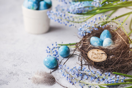 happy easter! decorated quail eggs in a nest on a light background