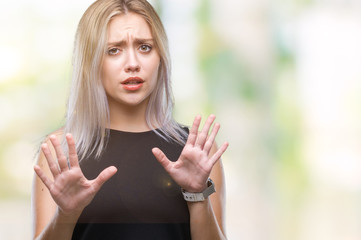 Young blonde woman over isolated background afraid and terrified with fear expression stop gesture with hands, shouting in shock. Panic concept.