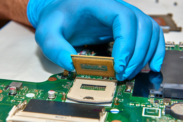 Hands of the technician repairing a computer, Technician who changes the computer's processor,...