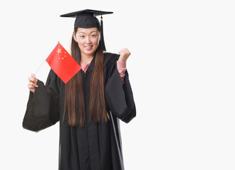 Young Chinese woman wearing graduate uniform holding China flag screaming proud and celebrating victory and success very excited, cheering emotion