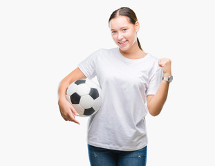 Young beautiful caucasian woman holding soccer football ball over isolated background screaming...