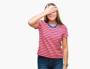 Fototapeta premium Young caucasian beautiful woman over isolated background smiling and laughing with hand on face covering eyes for surprise. Blind concept.