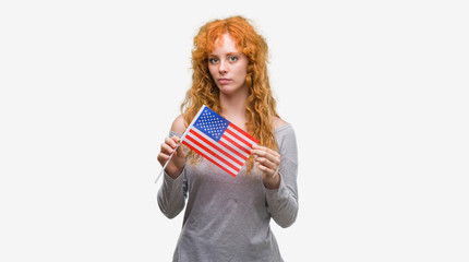 Young redhead woman holding flag of United States of America with a confident expression on smart face thinking serious