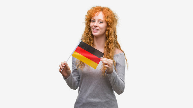 Young redhead woman holding flag of Germany with a happy face standing and smiling with a confident smile showing teeth