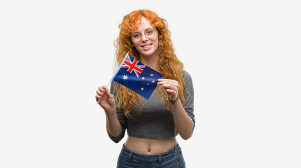 Young redhead woman holding flag of Australia with a happy face standing and smiling with a confident smile showing teeth