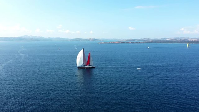 Video from above, aerial view of a beautiful sailing vessel and other yachts during a Regatta. September 2018, Sardinia, Italy.