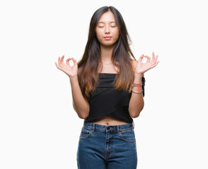 Fototapeta na wymiar Young asian woman over isolated background relax and smiling with eyes closed doing meditation gesture with fingers. Yoga concept.