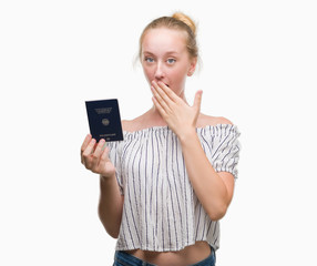 Fototapeta premium Blonde teenager woman holding passport of Germany cover mouth with hand shocked with shame for mistake, expression of fear, scared in silence, secret concept