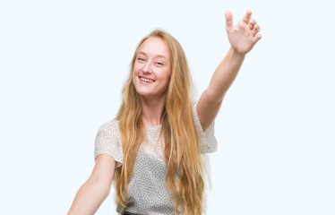 Blonde teenager woman wearing moles shirt looking at the camera smiling with open arms for hug. Cheerful expression embracing happiness.