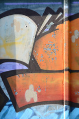 Fragment of graffiti drawings. The old wall decorated with paint stains in the style of street art culture. Colored background texture in warm tones