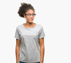 Young afro american woman wearing glasses over isolated background smiling looking side and staring away thinking.