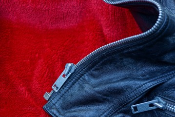 gray metal zip on a piece of leather clothes on red cloth