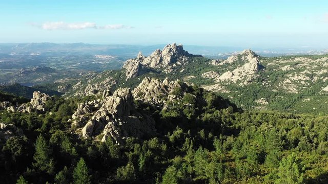 Video from above, aerial view of a beautiful valley surrounded by granite mountains and green vegetation, Monte Limbara, Sardinia, Italy.