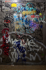 Fragment of graffiti tags. The old wall is spoiled with paint stains in the style of street art culture. Painted metal door