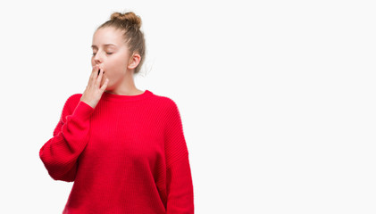 Young blonde woman wearing bun and red sweater bored yawning tired covering mouth with hand. Restless and sleepiness.